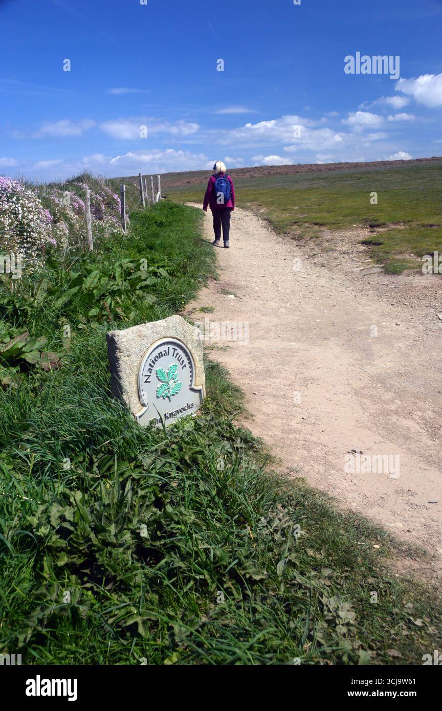 Woman Walking by Sign zum Knavocks Headland auf dem Cliff Path vom Godrevy Point in der Nähe von Hayle auf dem Southwest Costal Path, Cornwall, England, Großbritannien. Stockfoto