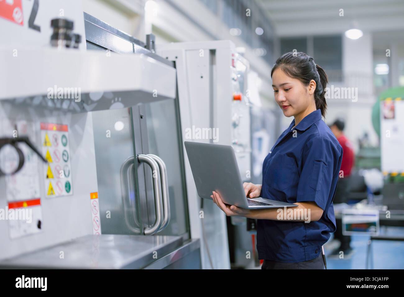 Junge Techniker Ingenieurarbeiterinnen arbeiten mit CNC-Drehmaschine in modernen Stahlindustriefabriken Stockfoto