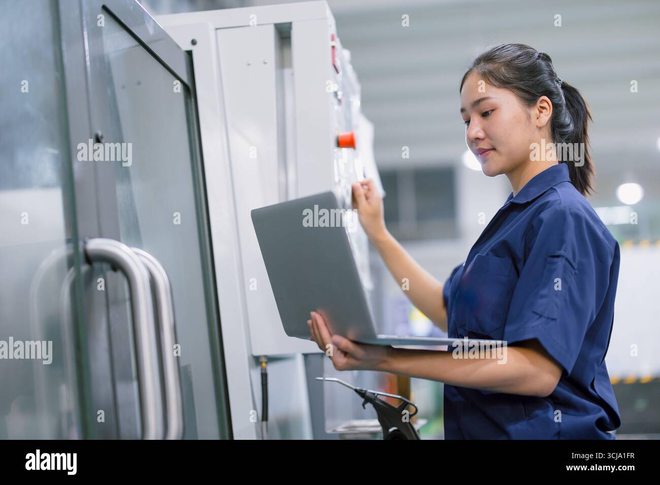 Junge Techniker Ingenieurarbeiterinnen arbeiten mit CNC-Drehmaschine in modernen Stahlindustriefabriken Stockfoto