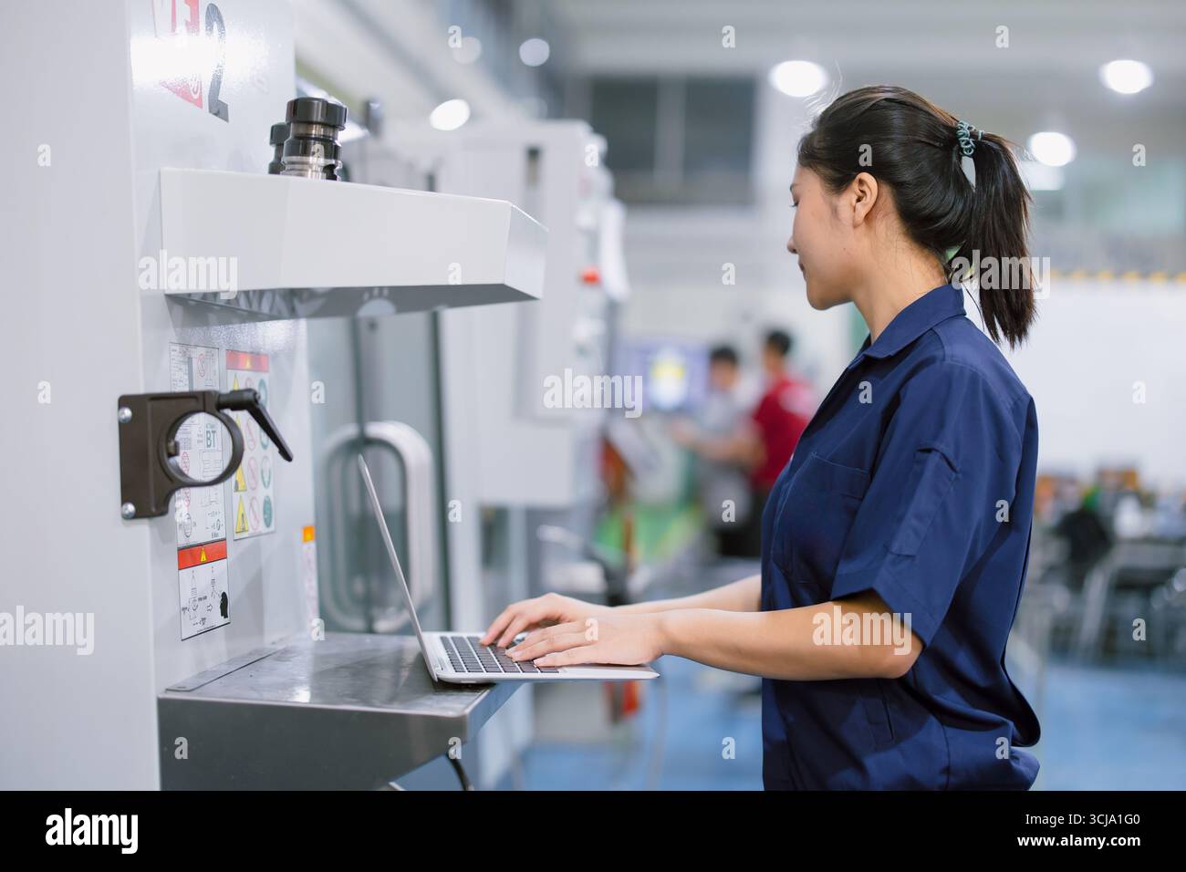 Junge Techniker Ingenieurarbeiterinnen arbeiten mit CNC-Drehmaschine in modernen Stahlindustriefabriken Stockfoto