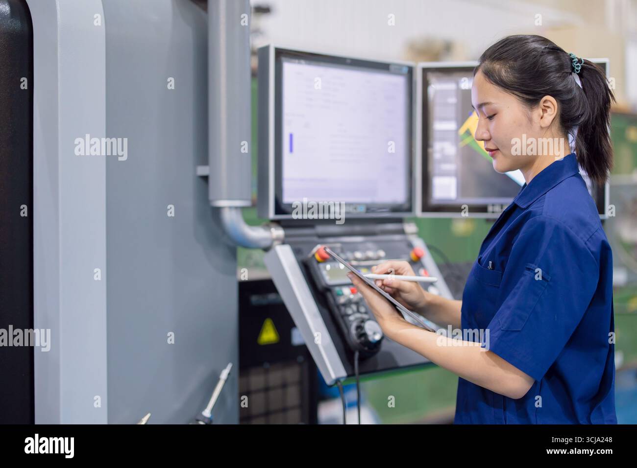 Junge Techniker Ingenieurarbeiterinnen arbeiten mit CNC-Drehmaschine in modernen Stahlindustriefabriken Stockfoto