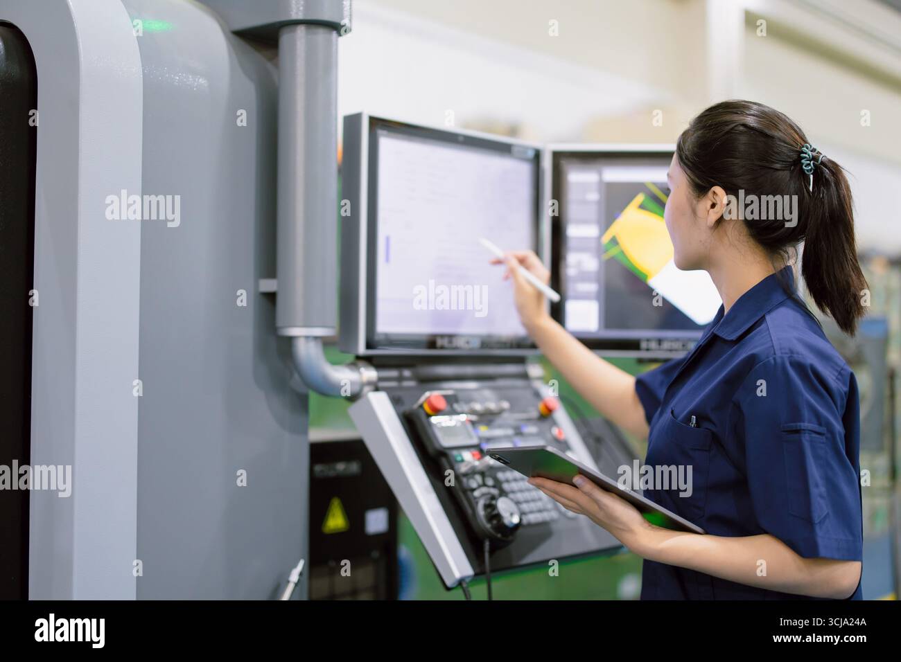 Junge Techniker Ingenieurarbeiterinnen arbeiten mit CNC-Drehmaschine in modernen Stahlindustriefabriken Stockfoto