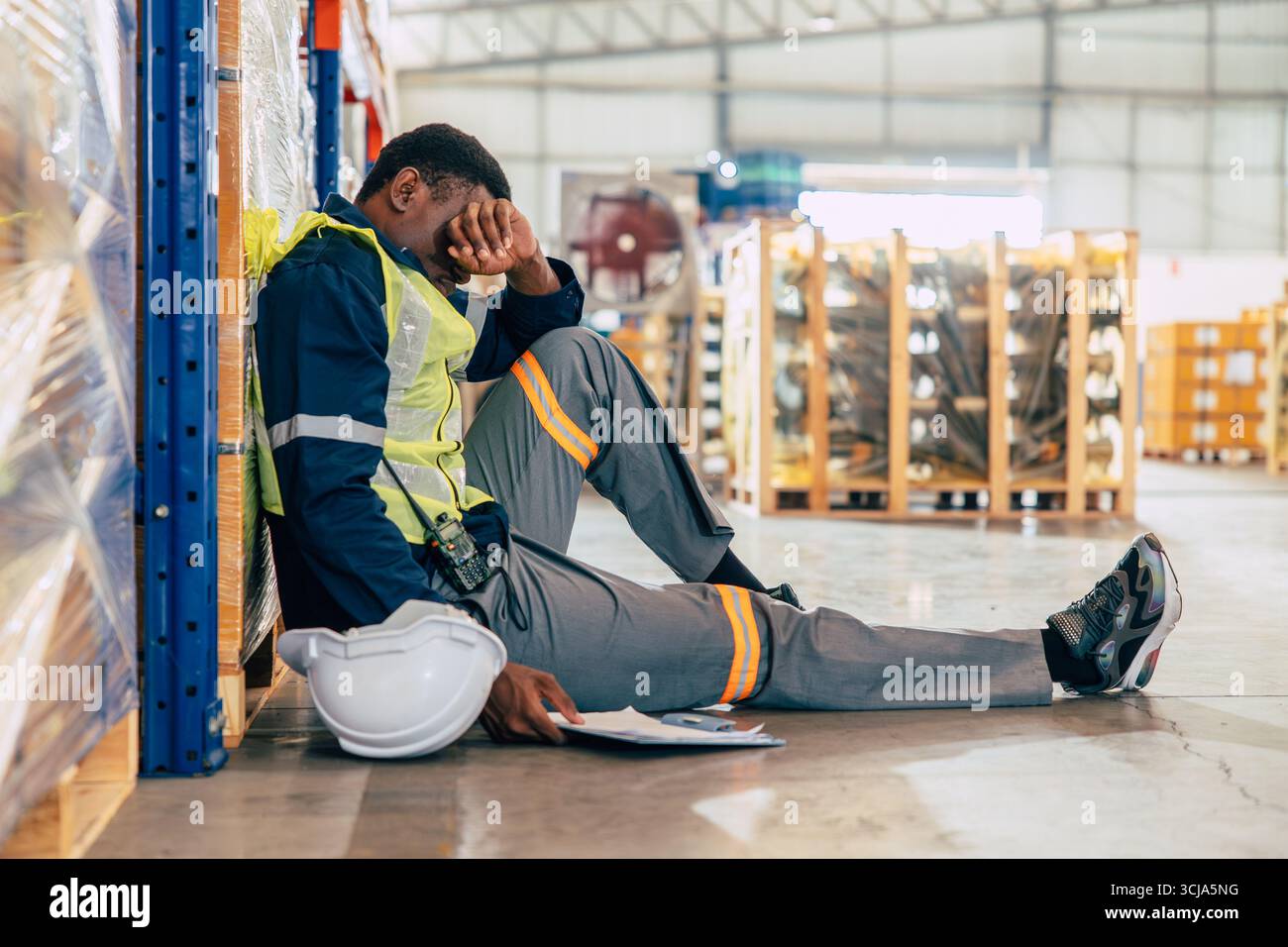 Stress der Mitarbeiter in der Industrie, unglückliche Menschen, ängstlicher Mann, langweilig am Arbeitsplatz, auf dem Boden sitzend, Sorgen Ausdruck Stockfoto