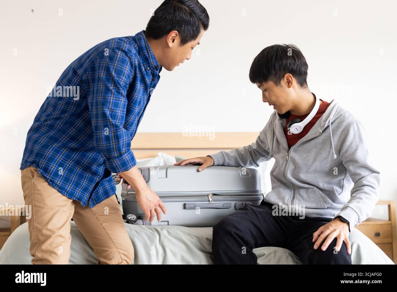Koffer packen, zwei asiatische Männer bereiten sich auf die Reise zu Hause vor Stockfoto
