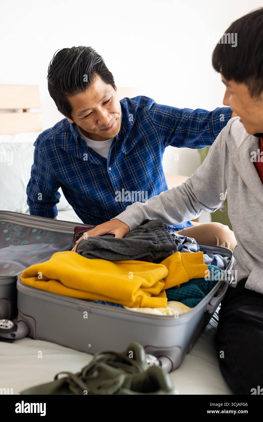 Vater und Sohn packen Koffer ins Bett und bereiten sich auf den gemeinsamen Familienausflug vor Stockfoto