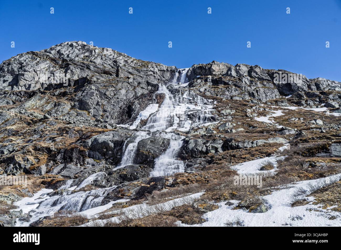Majestätische Landschaft mit einem ruhigen Tal, flankiert von schneebedeckten Bergen und einem sich windenden Fluss, alles unter einem klaren blauen Himmel, der Ruhe und Natu weckt Stockfoto