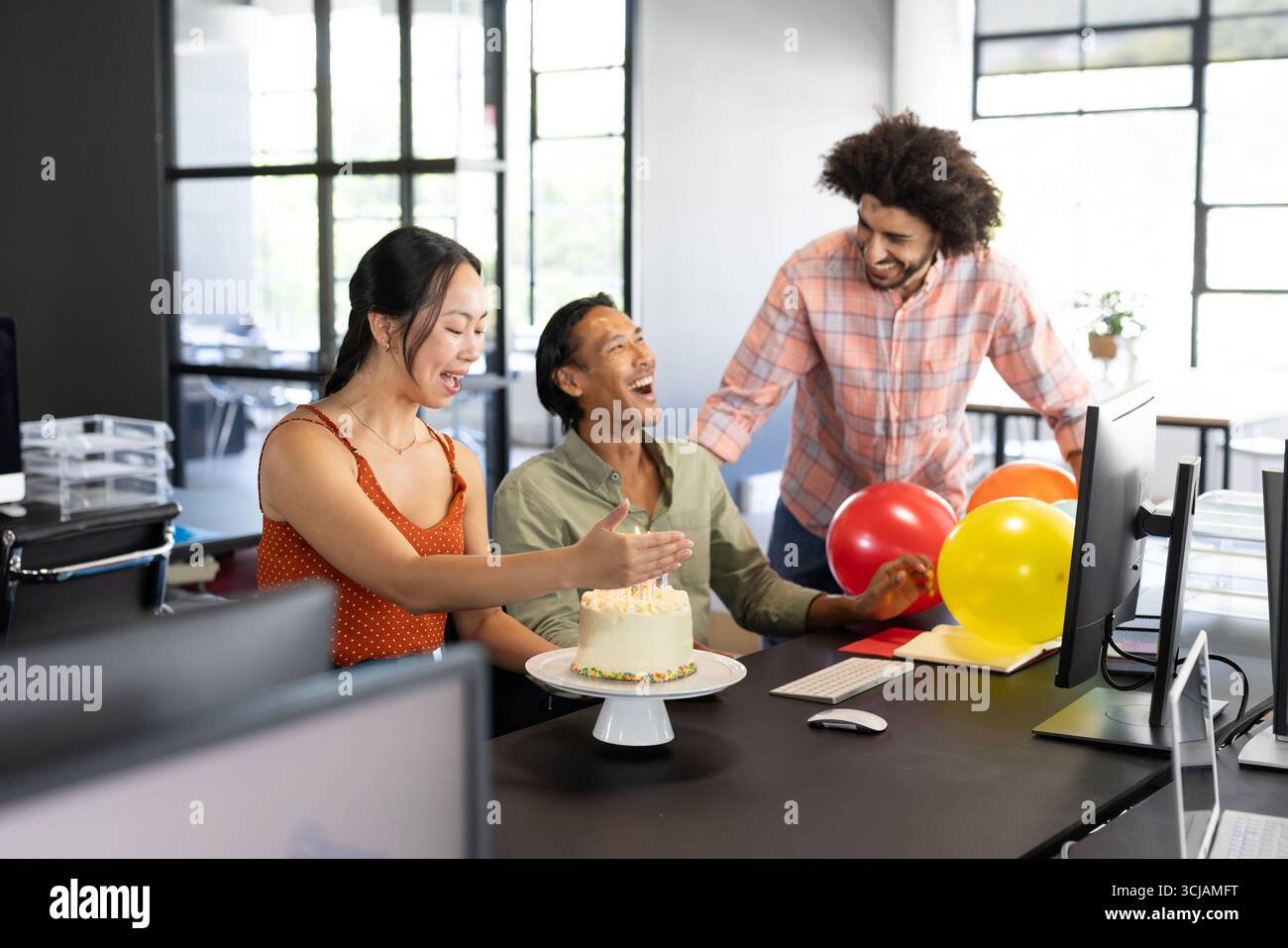 Im Büro feiern verschiedene Kollegen gemeinsam Geburtstag mit Kuchen und Ballons Stockfoto