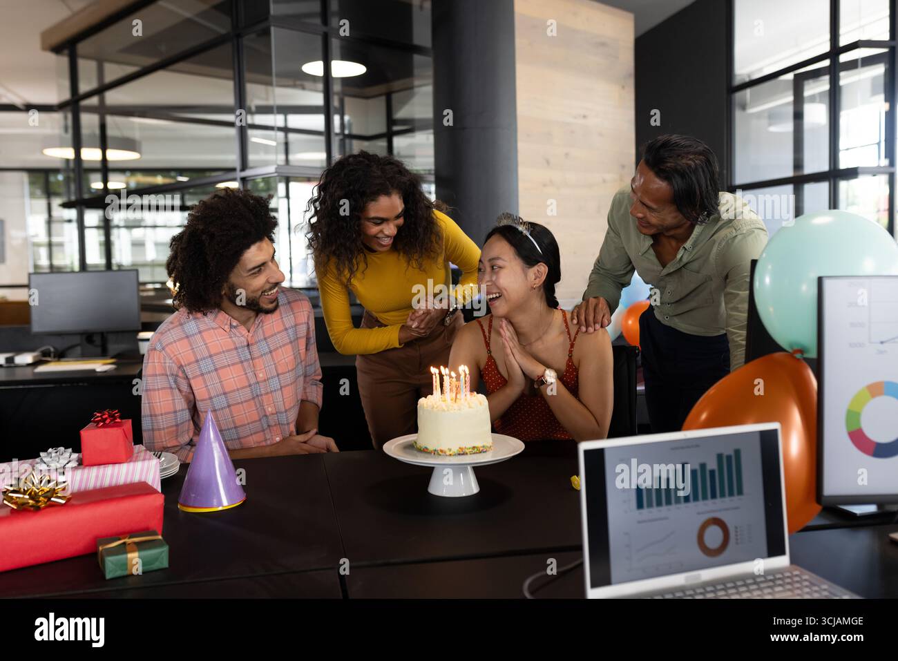 Im Büro versammeln sich Kollegen mit Kuchen und Geschenken zum Geburtstag um die Frau Stockfoto