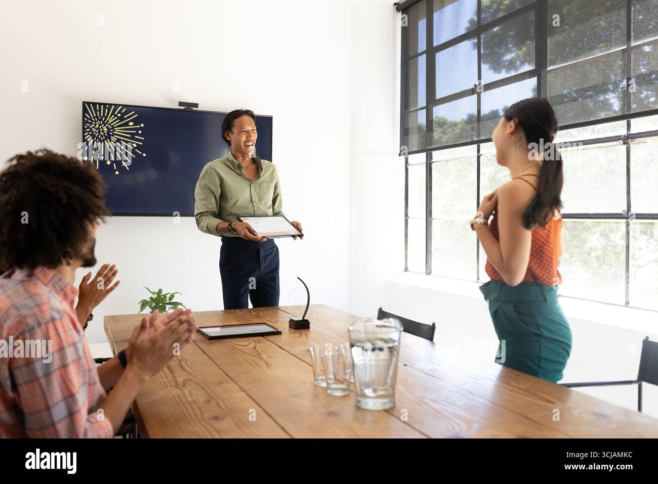 Geschäftsteam applaudiert den Kollegen, der während der Besprechung in einem modernen Büro ausgezeichnet wurde Stockfoto