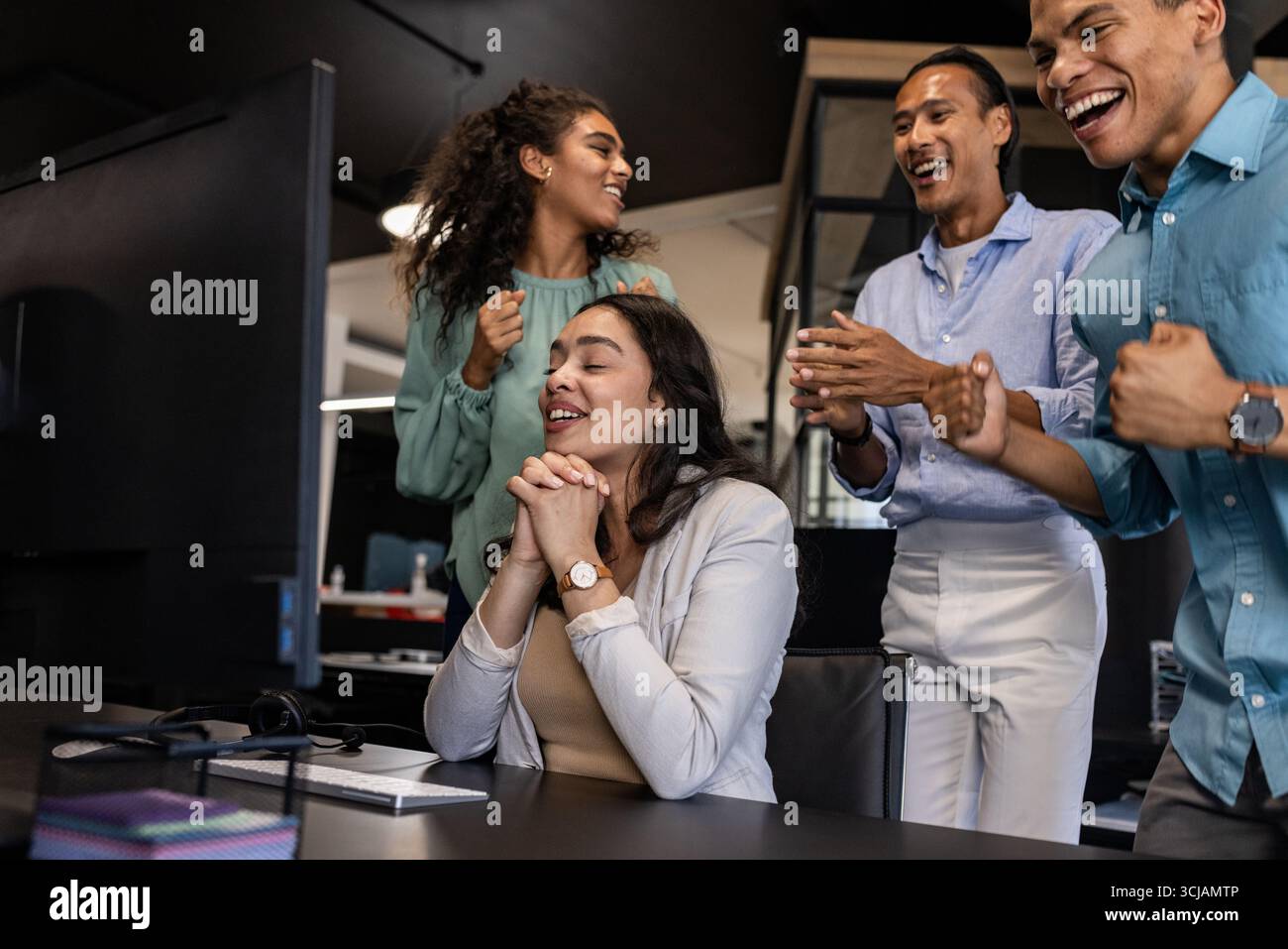 Vielseitiges Geschäftsteam feiert Erfolge im Büro, lächelt und klatscht zusammen Stockfoto