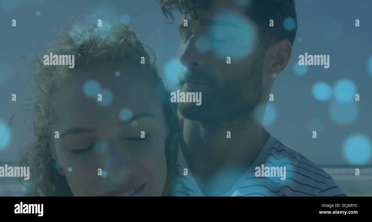 Stehende Paare tragen gestreiftes T-Shirt und legeres Oberteil am Sandstrand mit weichen blauen Lichtkreisen Stockfoto