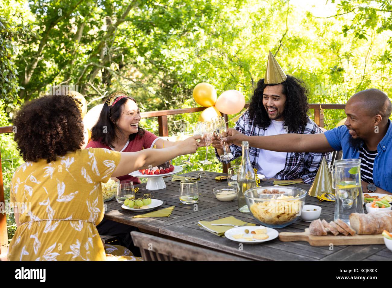 Freunde feiern im Freien und genießen Getränke am festlichen Tisch mit Snacks Stockfoto