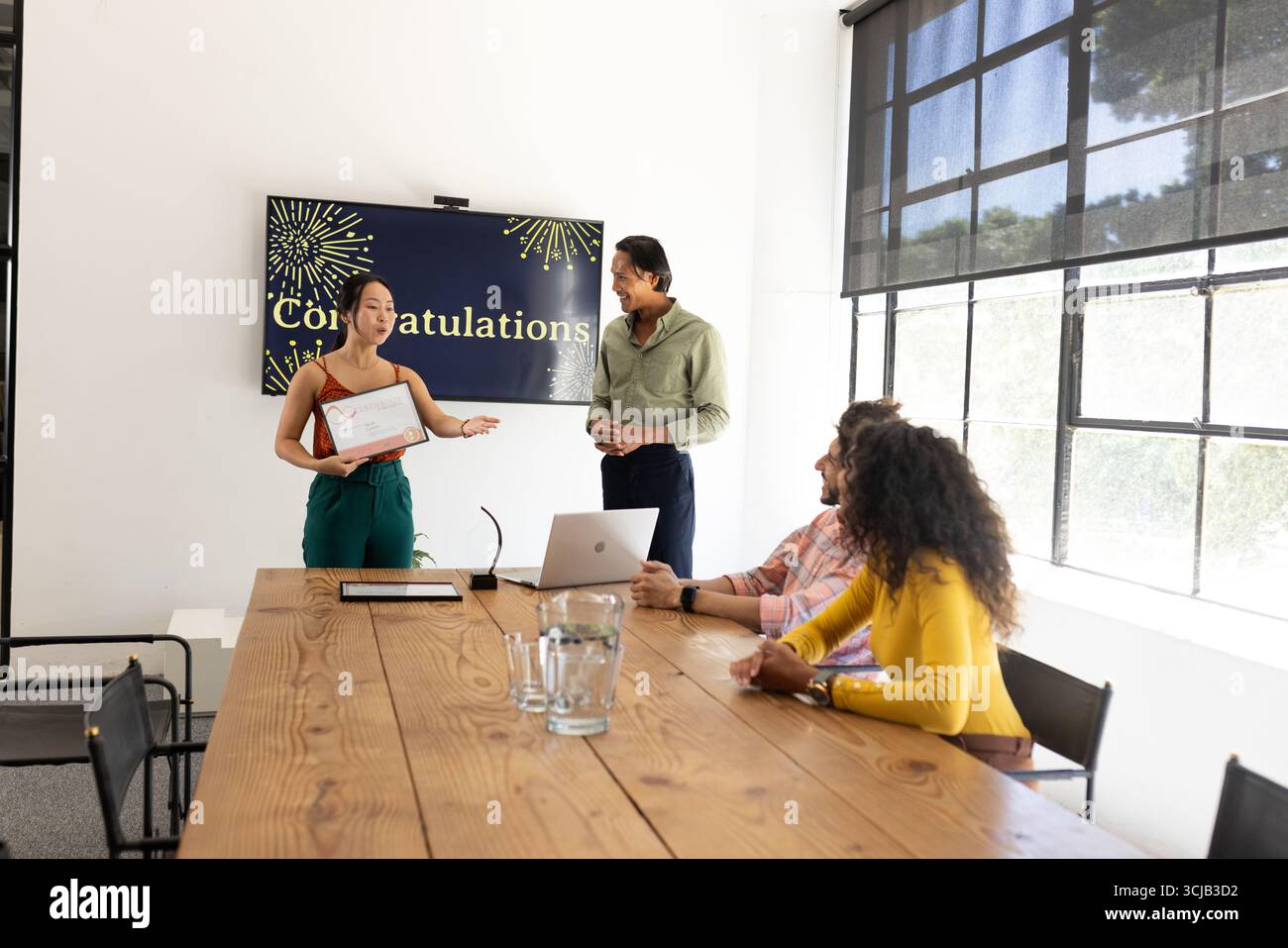 Team feiert Erfolg im Besprechungsraum im Büro, Frau erhält Auszeichnung Stockfoto