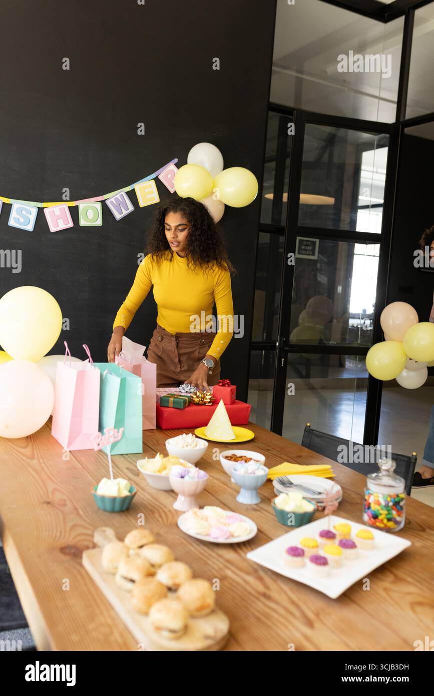 Frau bereitet Partytisch mit Snacks und Geschenken in der Bürofeier vor Stockfoto