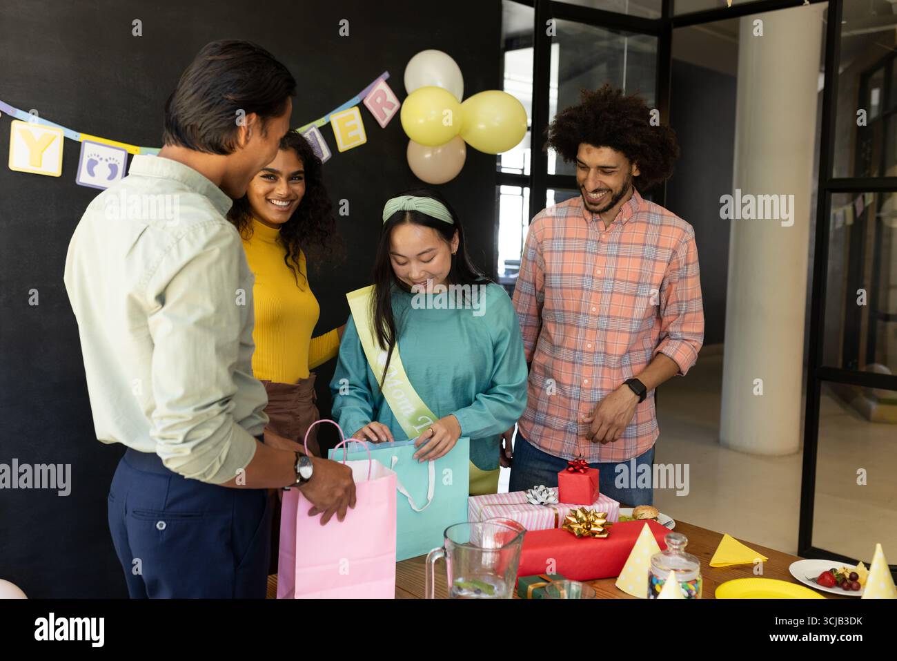 Im Büro tauschen verschiedene Kollegen Geschenke aus und feiern festliche Atmosphäre Stockfoto