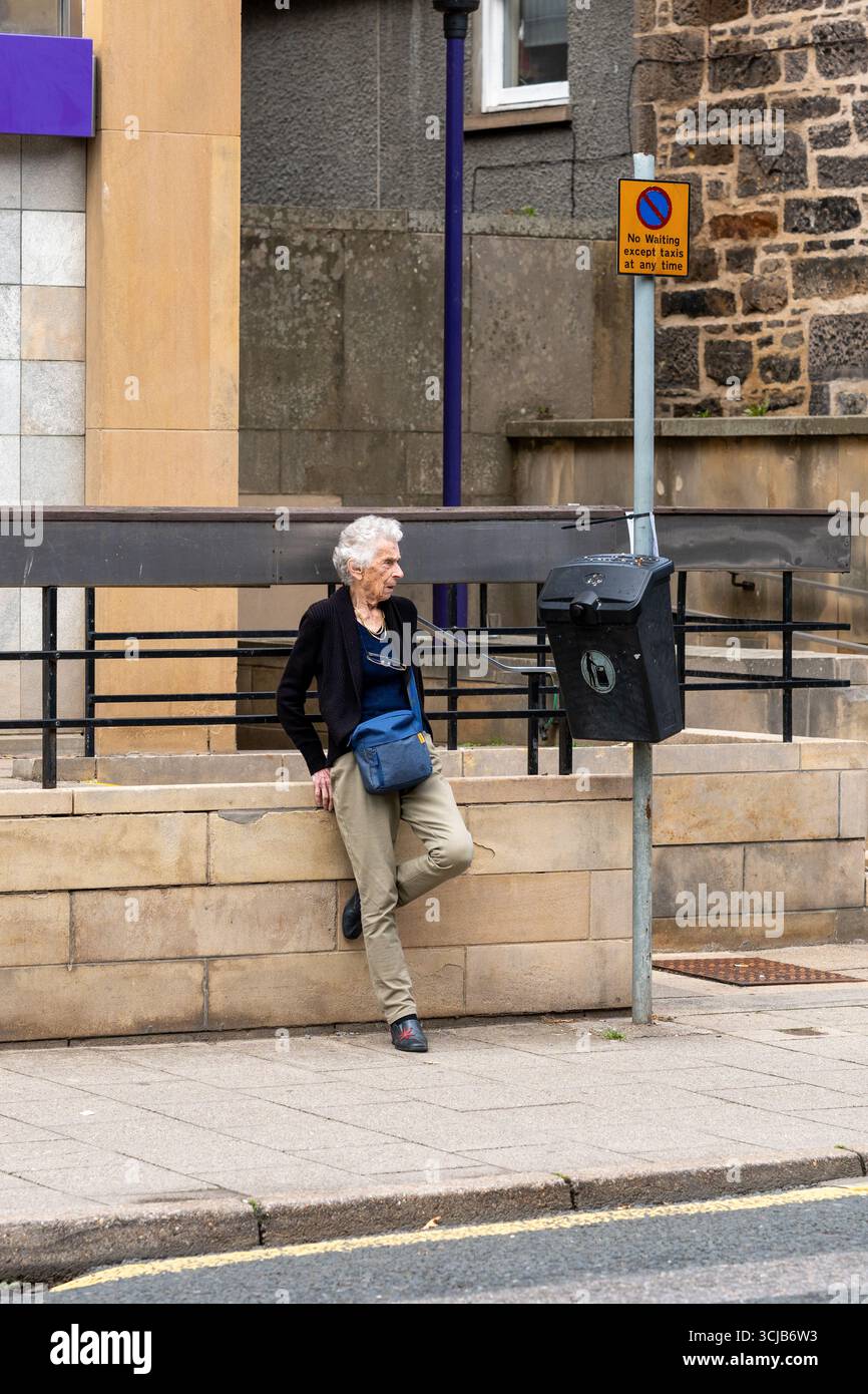 5. September 2025. Elgin, Moray, Schottland. Dies ist eine ältere Frau, die sich an den Wal neben dem Verkehrsschild „Warten“ lehnt Stockfoto