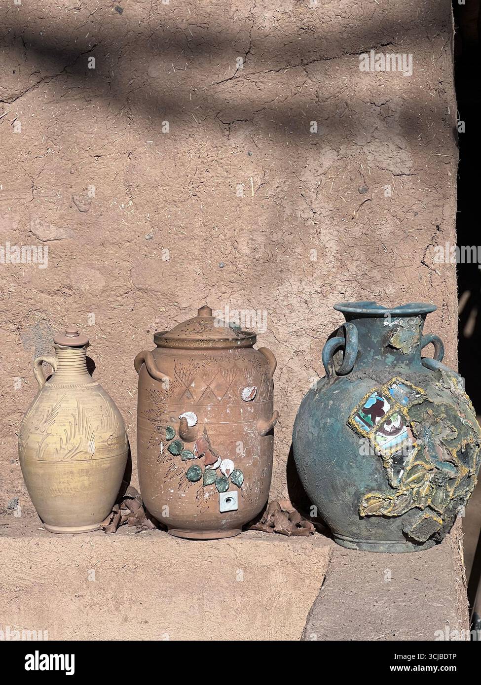 Traditionelle Tongefäße und Töpferwaren werden an einer lehmwand in einem denkmalgeschützten Gästehaus im Südiranischen ausgestellt. Stockfoto Traditionelle Tongefäße und Töpferwaren werden an einer lehmwand in einem denkmalgeschützten Gästehaus im Südiranischen ausgestellt. Stockfoto