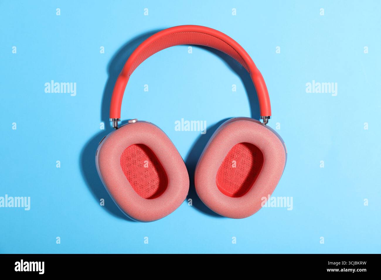 Ein Paar stilvoller rosafarbener Kopfhörer auf hellblauem Hintergrund, Draufsicht Stockfoto