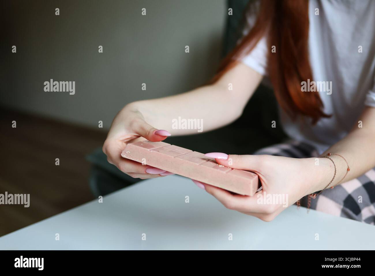 Mädchen zeigt rosa Dessertbar, stilvolle Maniküre im Fokus. Stockfoto