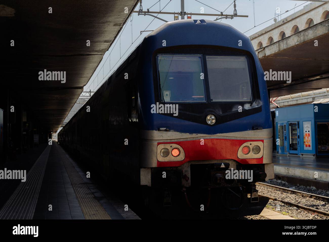 Moderner blauer Personenzug, der an einem Bahnsteig unter einem Dach steht. Konzept des öffentlichen Verkehrs, des Verkehrs, des Pendelverkehrs, der Eisenbahninfrastruktur Stockfoto