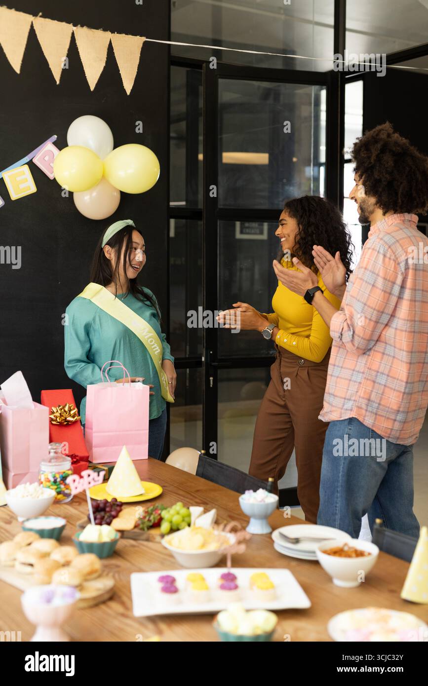 Feiert im Büro, Kollegen klatschen mit Schärpe am Partytisch für eine Frau Stockfoto