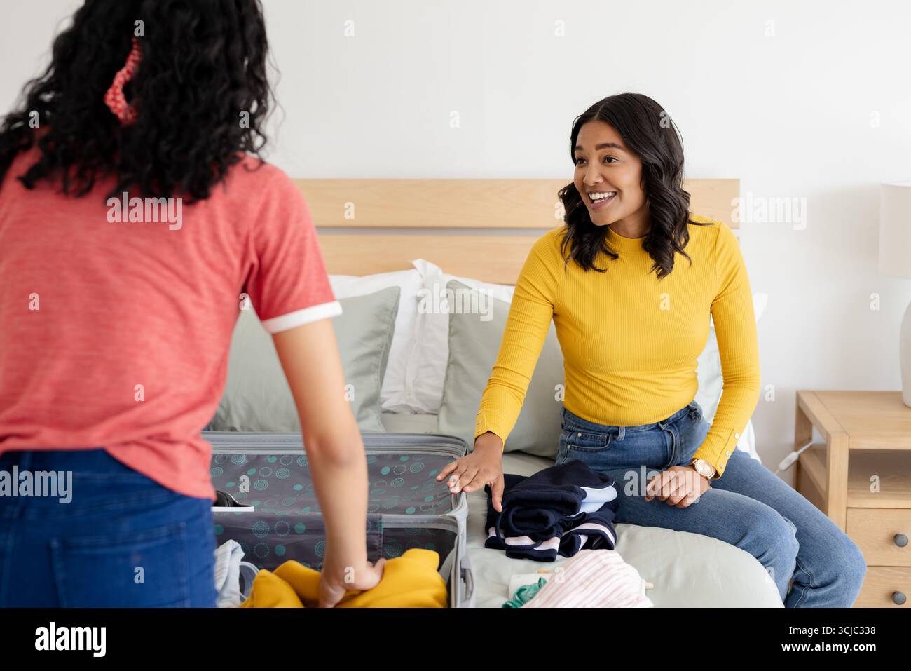 Mutter und Tochter packen Koffer ins Bett und bereiten sich auf den Familienausflug vor Stockfoto