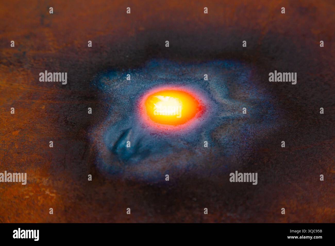 Die Oberfläche aus rostigem Metall mit einer zu rot erwärmten Stahlstelle. Stockfoto