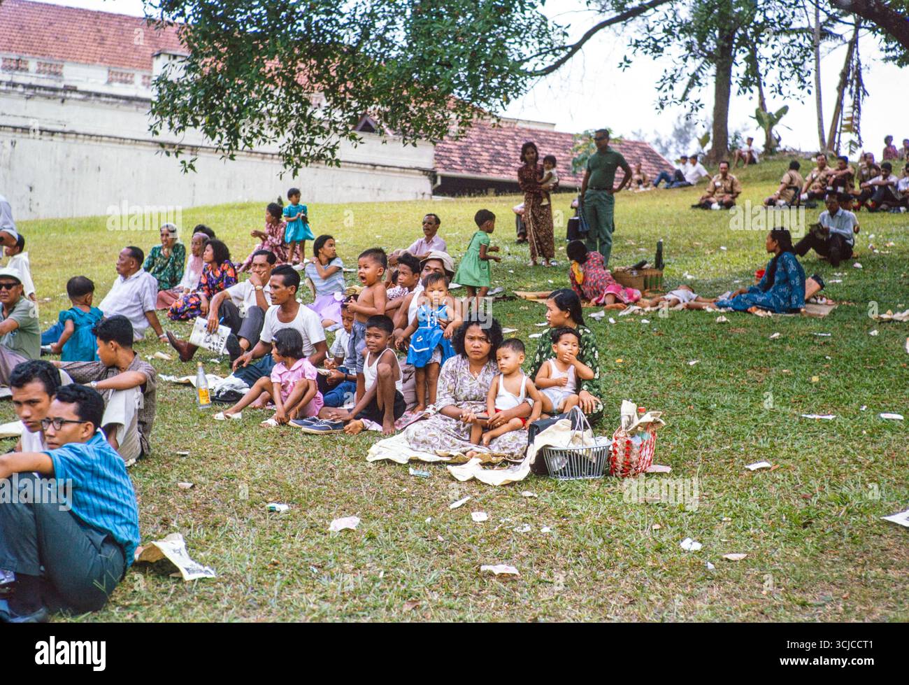 Familien, die auf einem Hügel sitzen und Motorrennen in Singapur oder Johor Bahru, Malaysia, Südostasien, 1964 beobachten Stockfoto