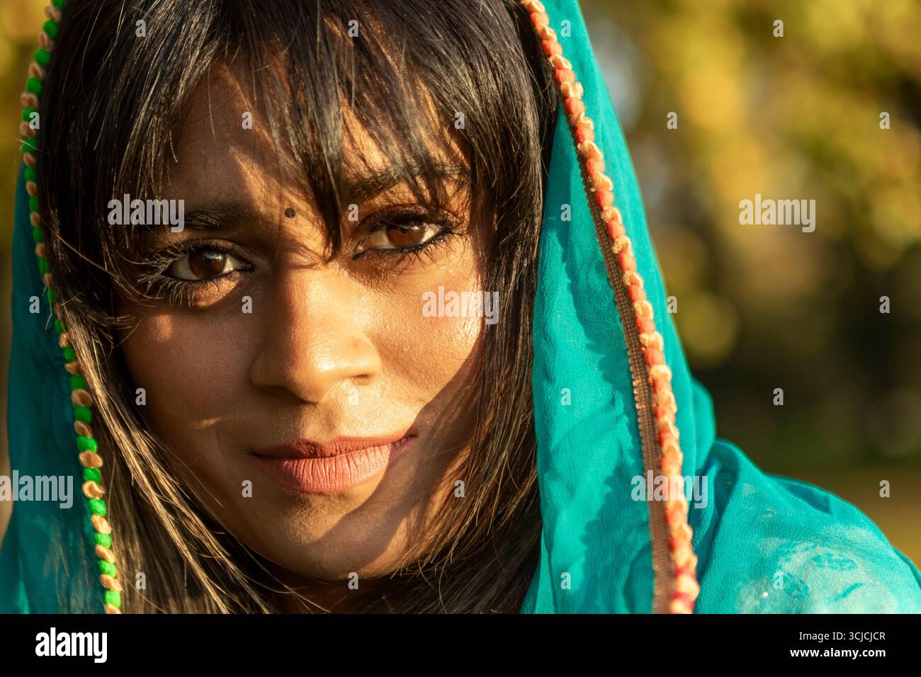 Ein Nahporträt einer Indianerin, die eine lebhafte traditionelle Dupatta trägt. Ihre ausdrucksstarken Augen und ihr heiterer Ausdruck erfassen das Wesen des kulturellen Lebens Stockfoto