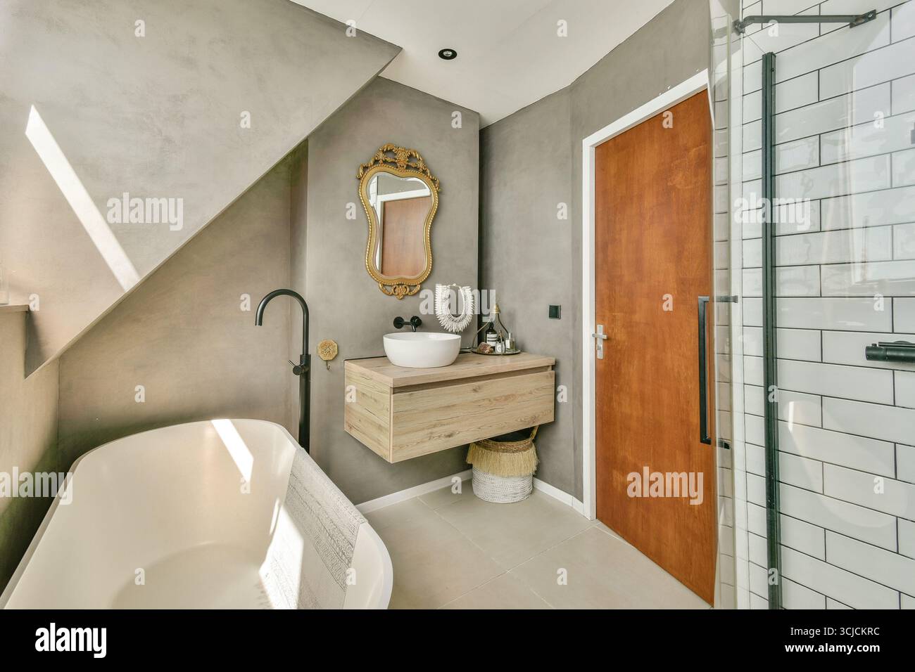 Modernes Bad mit eleganter Badewanne, elegantem Spiegel und Holzwaschtisch. Neutrale Töne schaffen ein ruhiges Ambiente im Raum Stockfoto