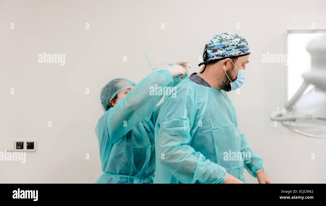 Zwei Zahnärzte in Peelings und Masken bereiten sich auf ein Transplantationsverfahren in einer modernen Zahnklinik vor und betonen Sauberkeit und Teamarbeit in Pati Stockfoto
