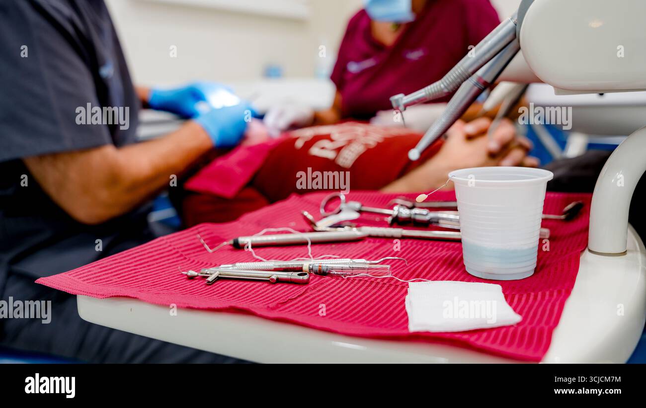Eine Sammlung von Implantatwerkzeugen wird auf einer roten Matte in einer klinischen Umgebung angezeigt, die für einen zahnärztlichen Eingriff bereit ist. Die Einstellung schlägt einen Profi vor Stockfoto