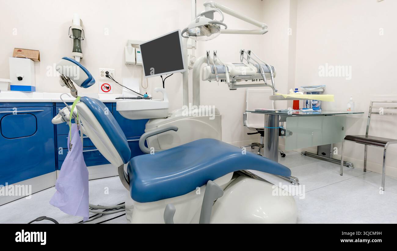 Ein zeitgenössischer Raum für Zahnmedizin mit modernen Zahngeräten und Werkzeugen. Das Zimmer hat ein sauberes, klinisches Design mit einem Zahnarztstuhl und hellem Licht Stockfoto