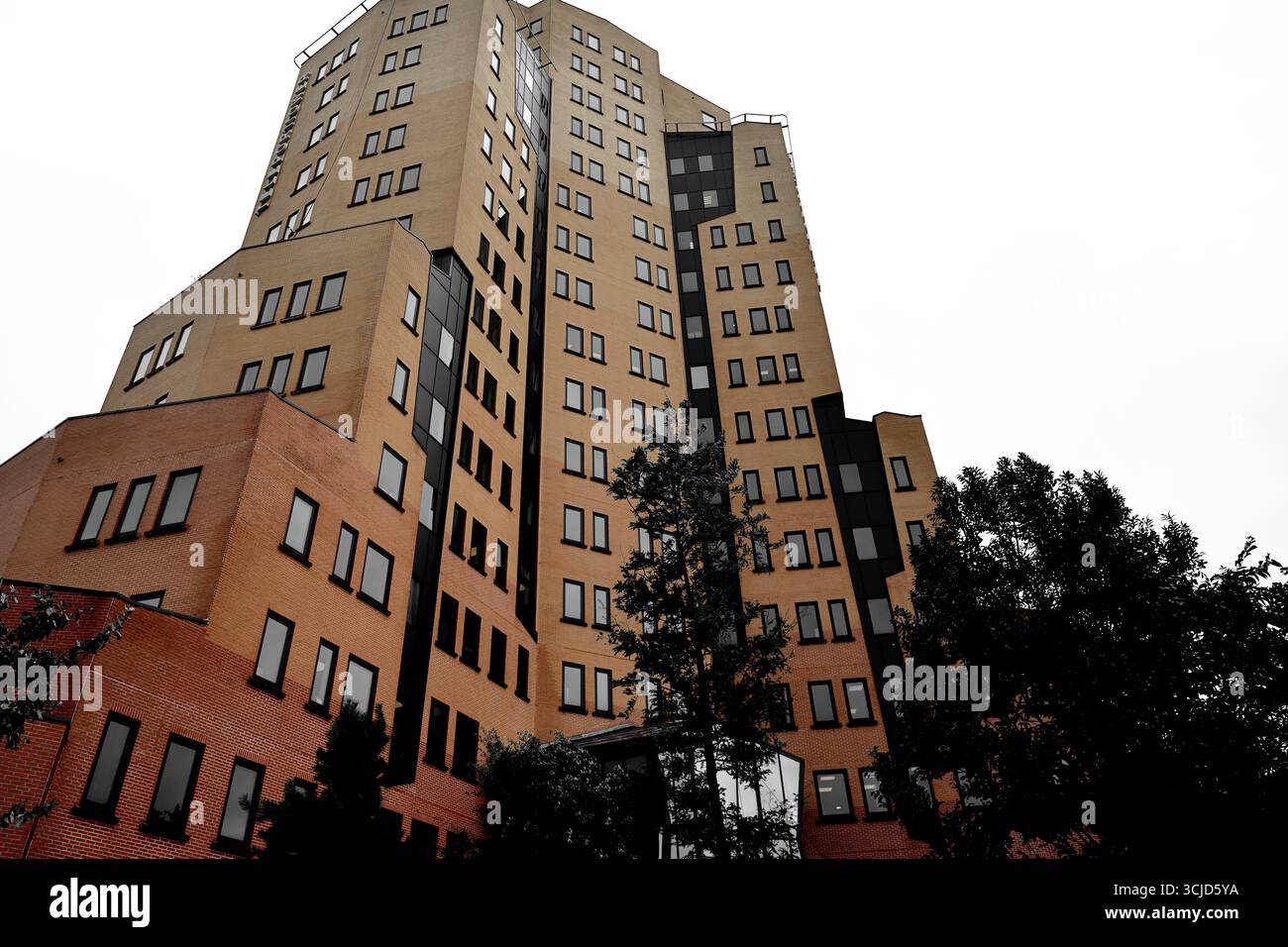 Weitwinkelansicht der Teleport Towers, Sloterdijk, Amsterdam, Niederlande, mit Regus Büros, versetzte Ziegelflügel, dunkle Paneele und Bäume gegen den Himmel. Stockfoto