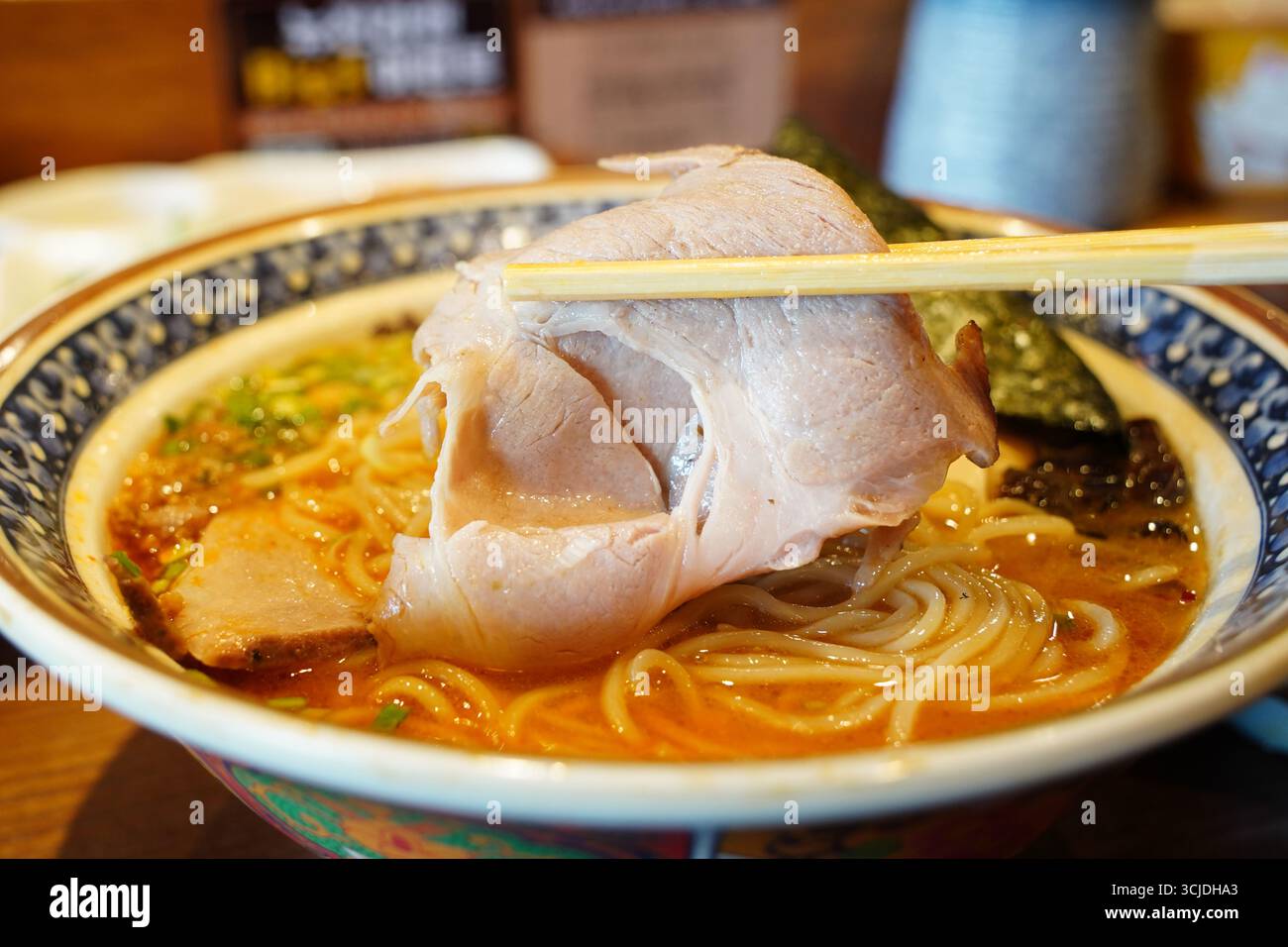Japanischer Ramen mit großem Chashu-Schweinefleisch, das von Stäbchen gehoben wird Stockfoto