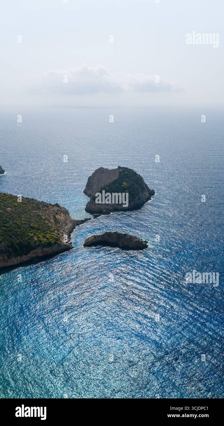 Luftbild der Insel Agios Andreas Höhleninsel mit steilen Klippen, türkisfarbenem Wasser und üppiger grüner Vegetation, die einen Hügel über der Küste bedeckt Stockfoto