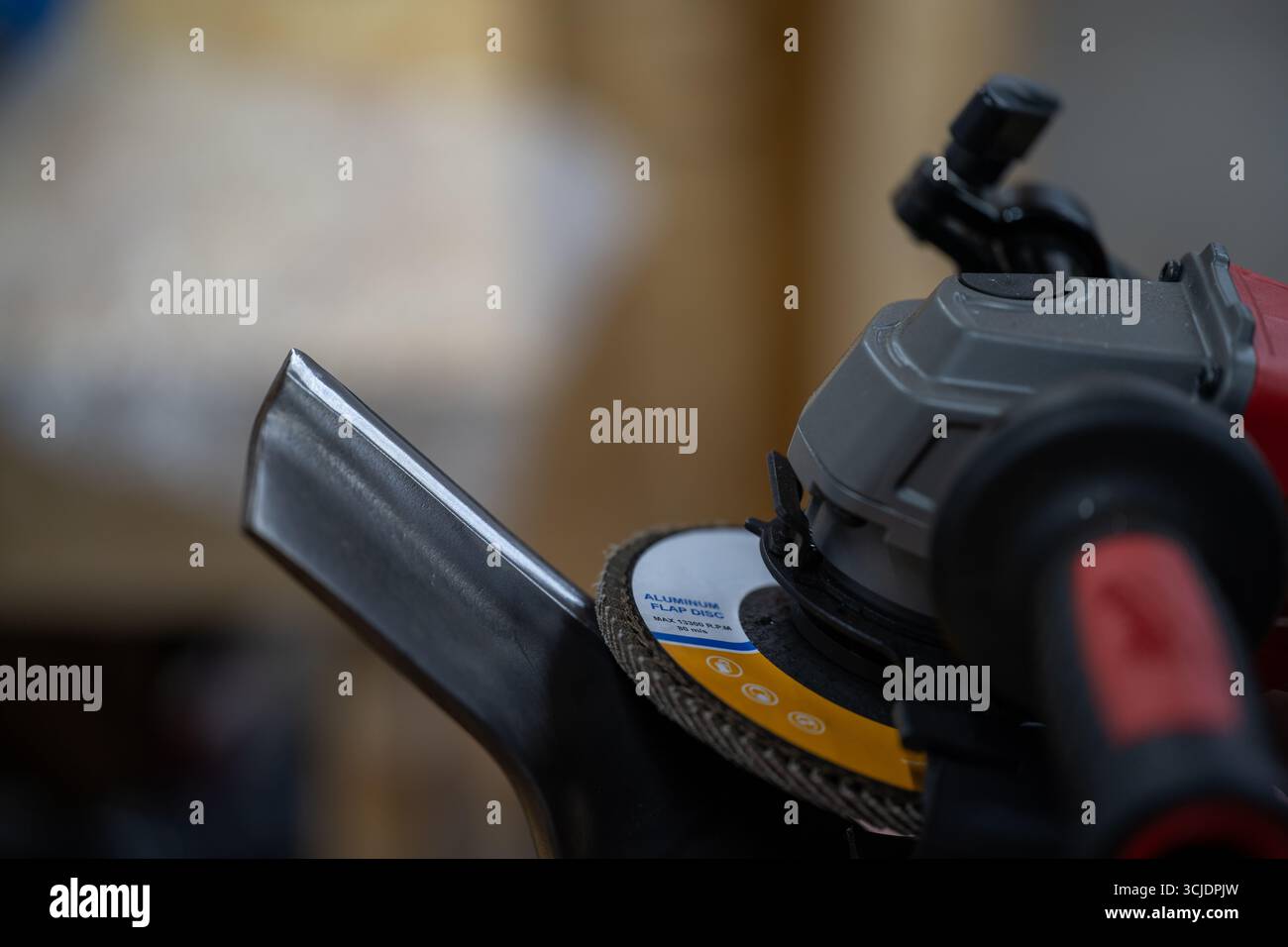 Winkelschleifer mit Klappscheibe an Metallkante Stockfoto