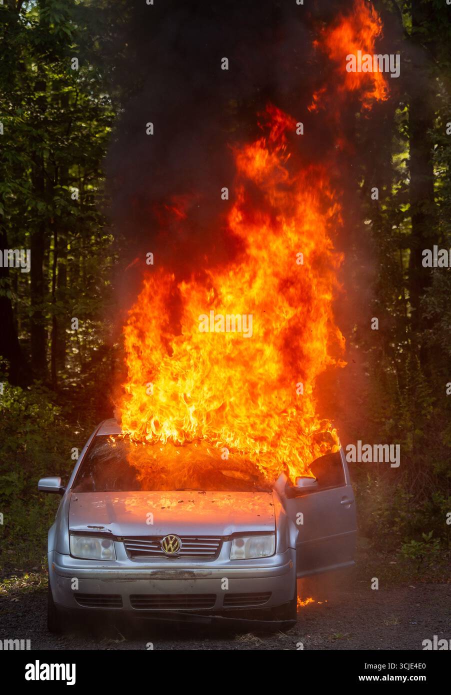Feuerwehrleute bekämpfen ein brennendes Autofeuer mit starkem Rauch und Flammen und zeigen Notfallmaßnahmen, Brandschutz und dramatische Rettungsaktionen. Stockfoto