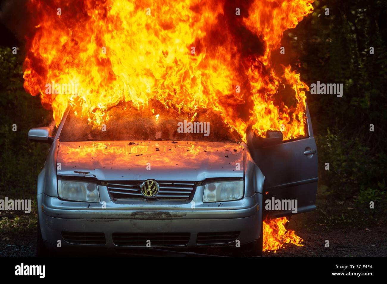 Feuerwehrleute bekämpfen ein brennendes Autofeuer mit starkem Rauch und Flammen und zeigen Notfallmaßnahmen, Brandschutz und dramatische Rettungsaktionen. Stockfoto