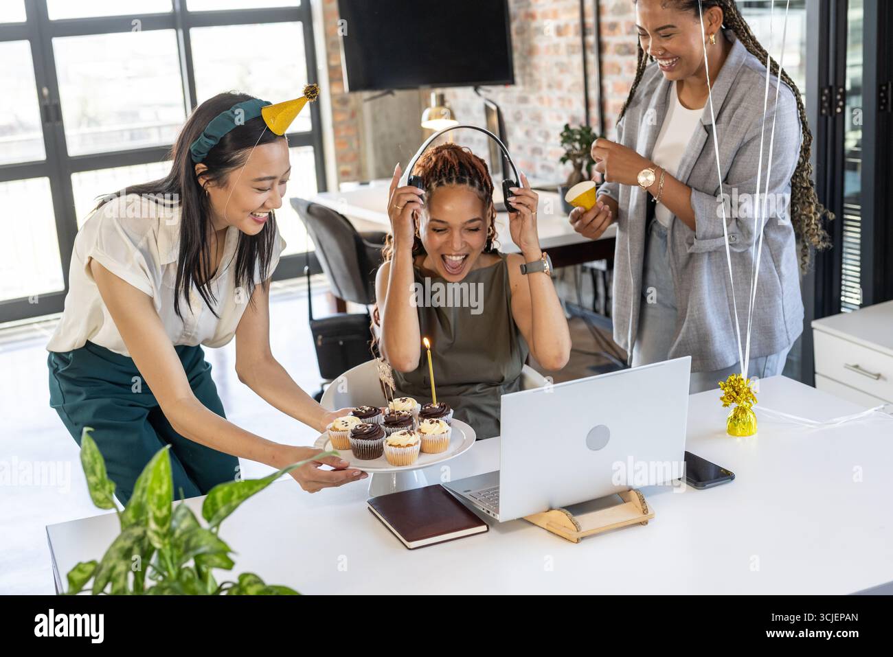 Kollegen feiern Geburtstag im Büro mit Cupcakes und fröhlichem Lachen Stockfoto