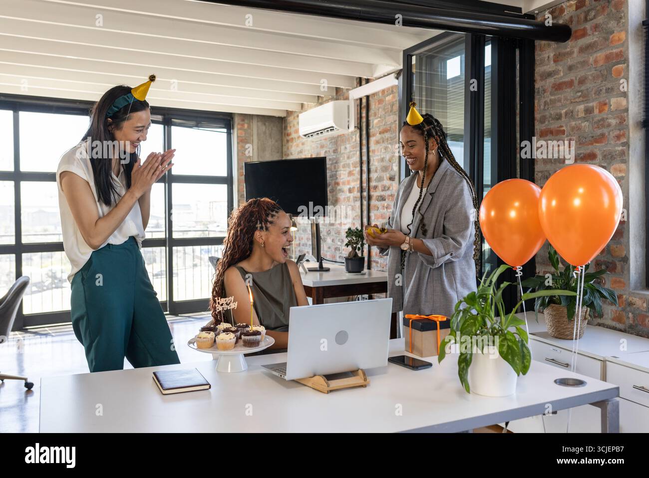 Feiert Geburtstag im Büro, Kollegen mit Cupcakes, Ballons und Partyhüten Stockfoto