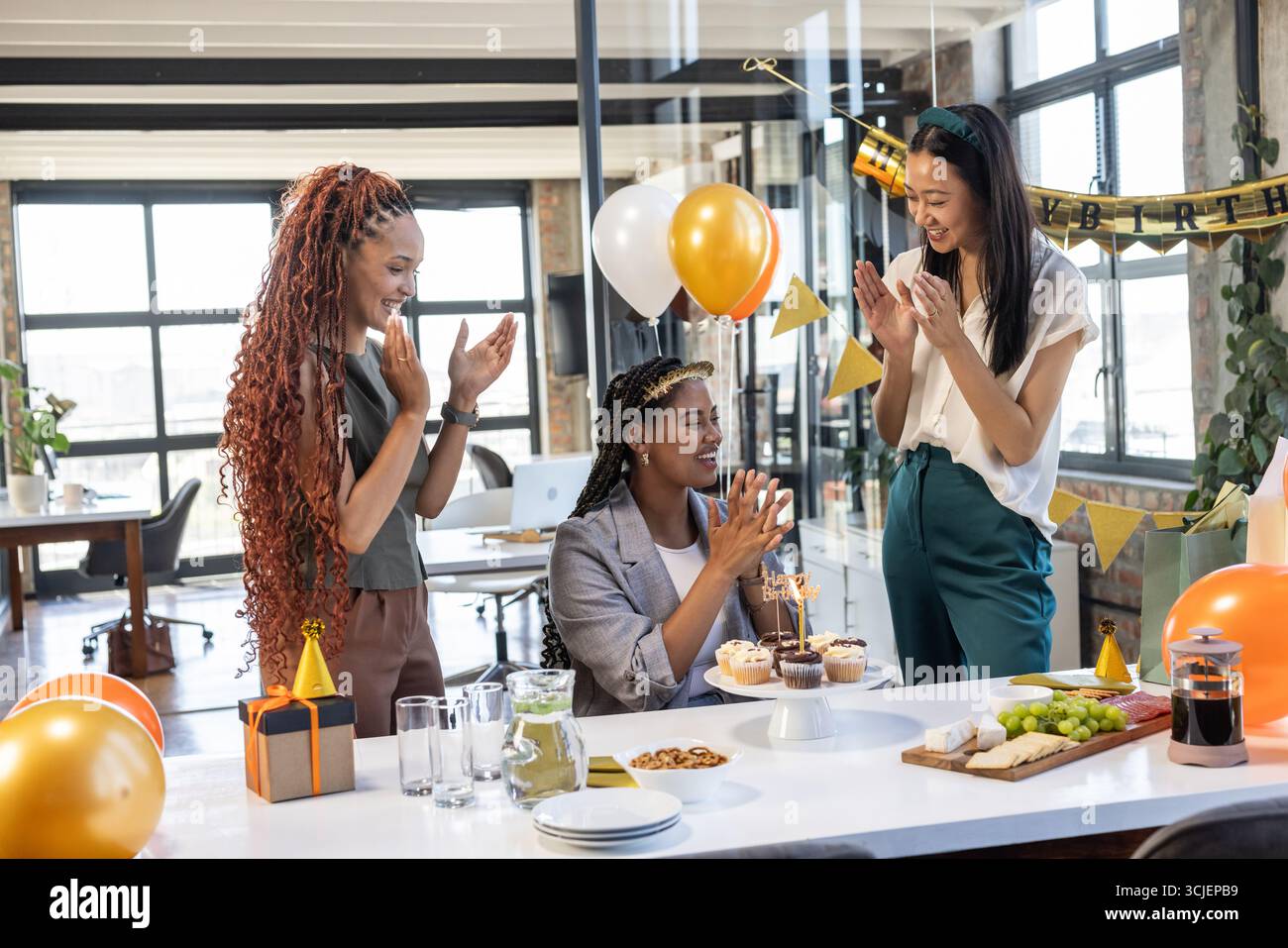 Kollegen feiern im Büro Geburtstag mit Kuchen, Ballons und fröhlichem Klatschen Stockfoto