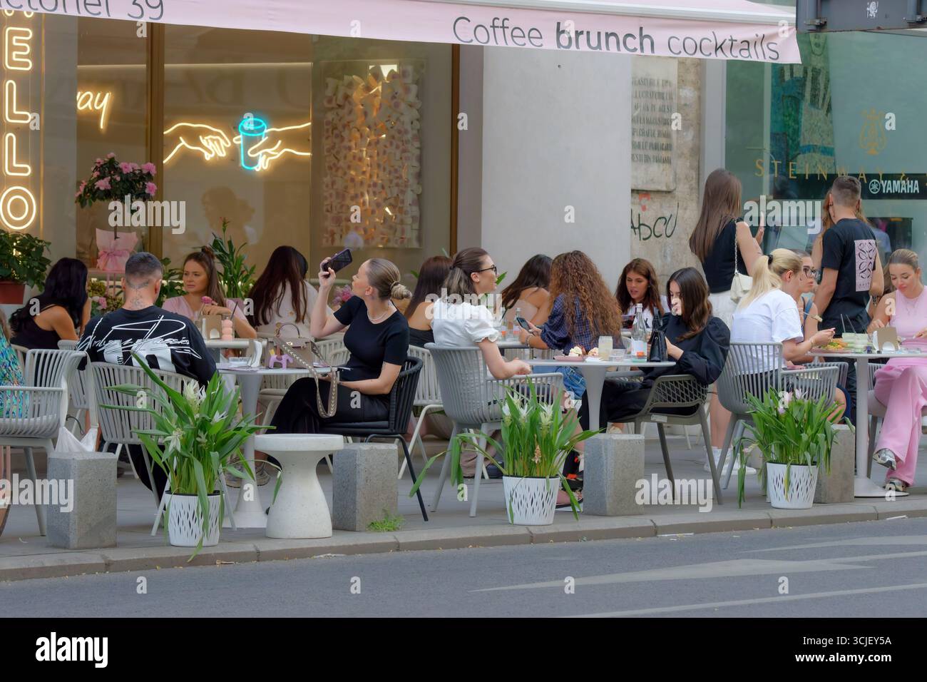 Junge Leute, die sich in einem Terrassen-Restaurant auf dem Bürgersteig einer städtischen Straße entspannen Stockfoto