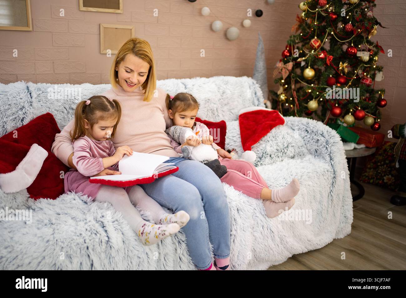 Mutter liest ihren Töchtern auf dem Sofa eine Weihnachtsgeschichte vor Stockfoto