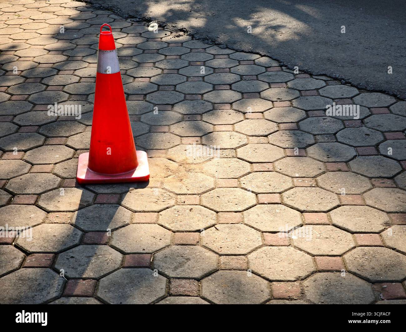Ein kegelförmiges Schild steht auf einem Bürgersteig aus Betonstein Stockfoto