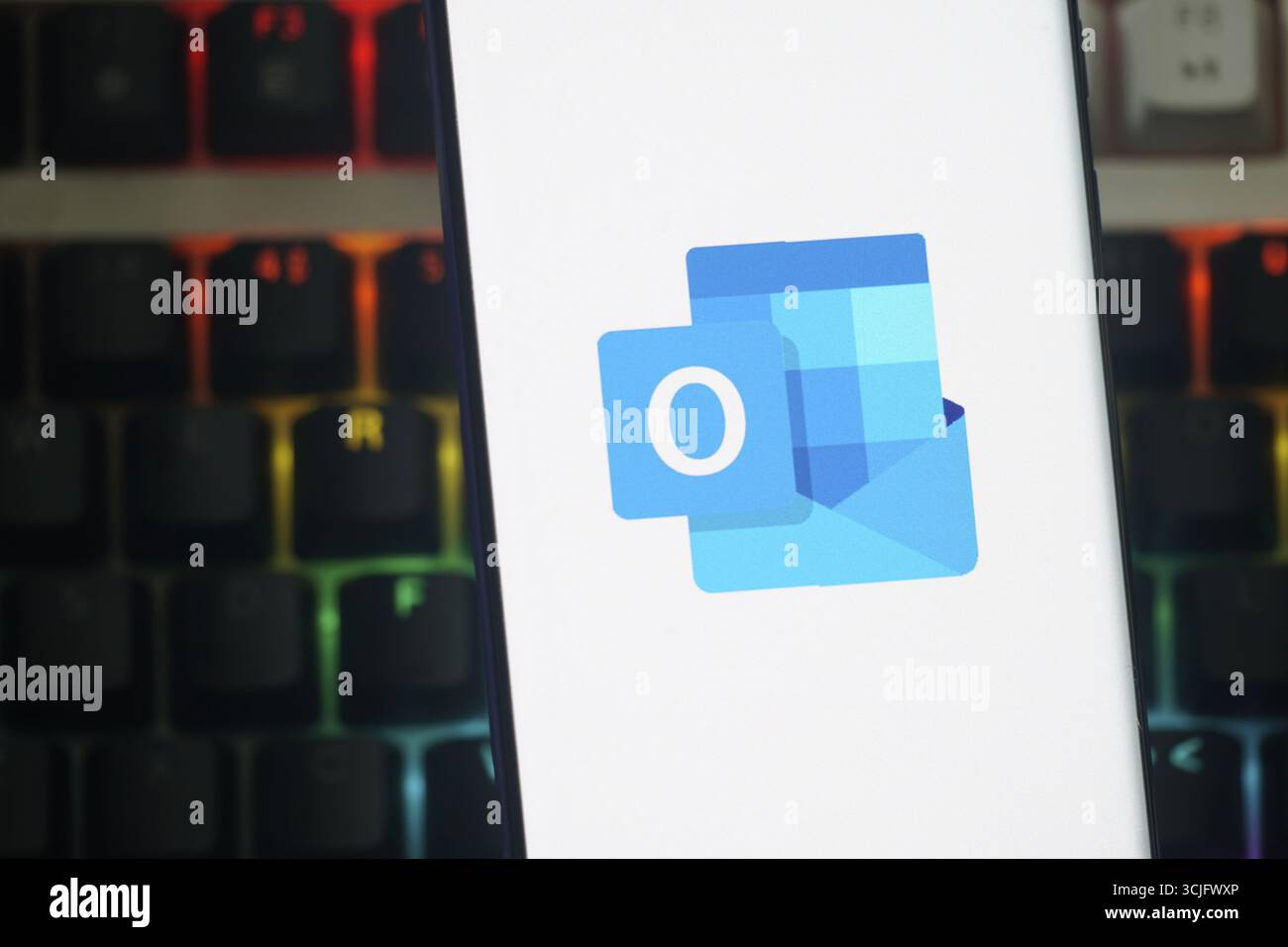 Outlook-Logo wird auf einem Smartphone-Bildschirm vor einem Tastaturhintergrund angezeigt Stockfoto
