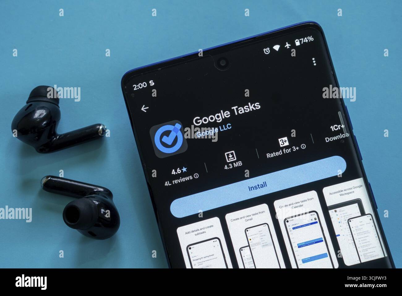 Smartphone zeigt Google Tasks App mit schwarzen Ohrstöpseln vor blauem Hintergrund Stockfoto