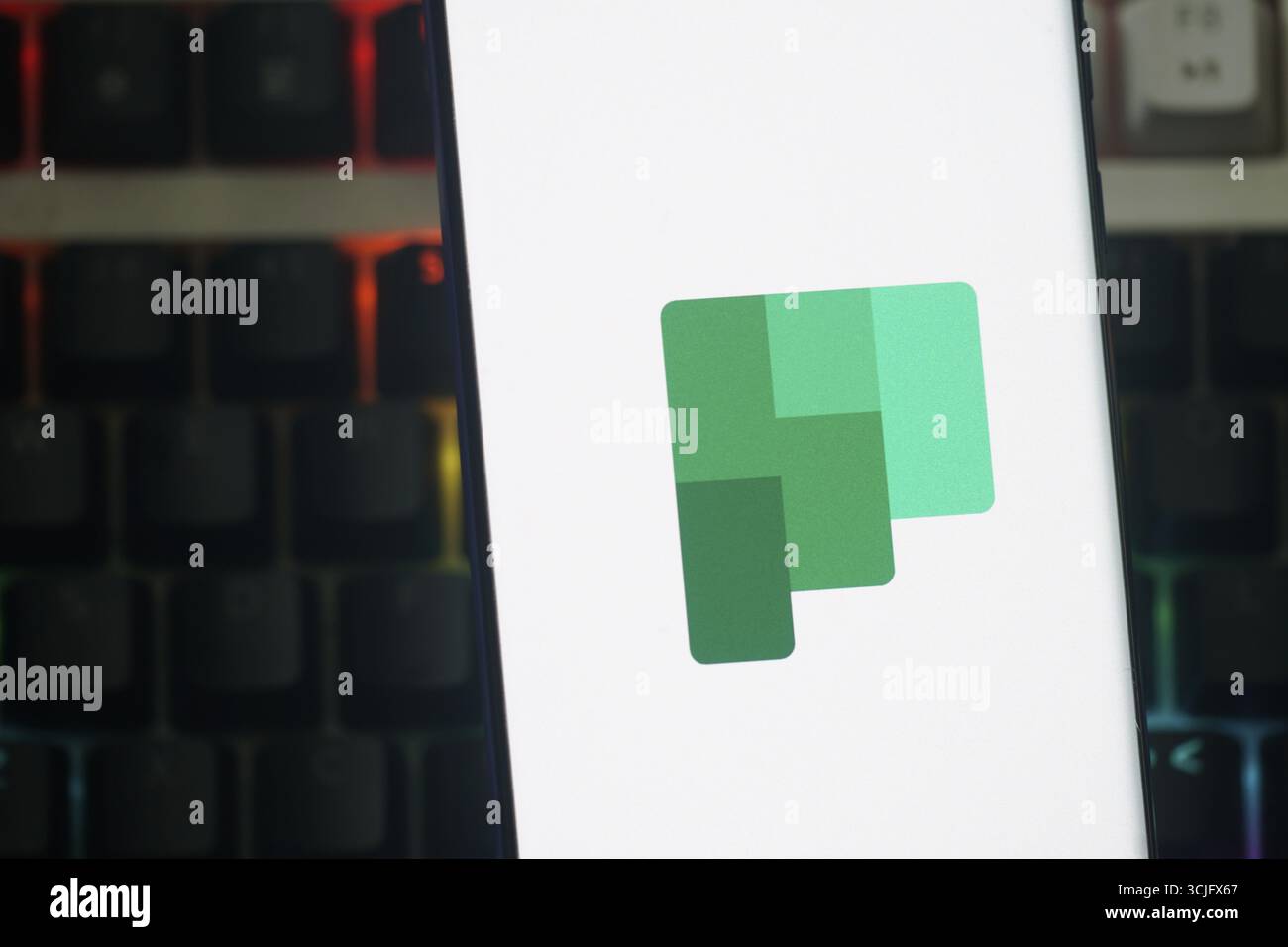 Das Microsoft Planner-Logo wird auf einem Smartphone-Bildschirm mit einem lebendigen Tastaturhintergrund angezeigt Stockfoto