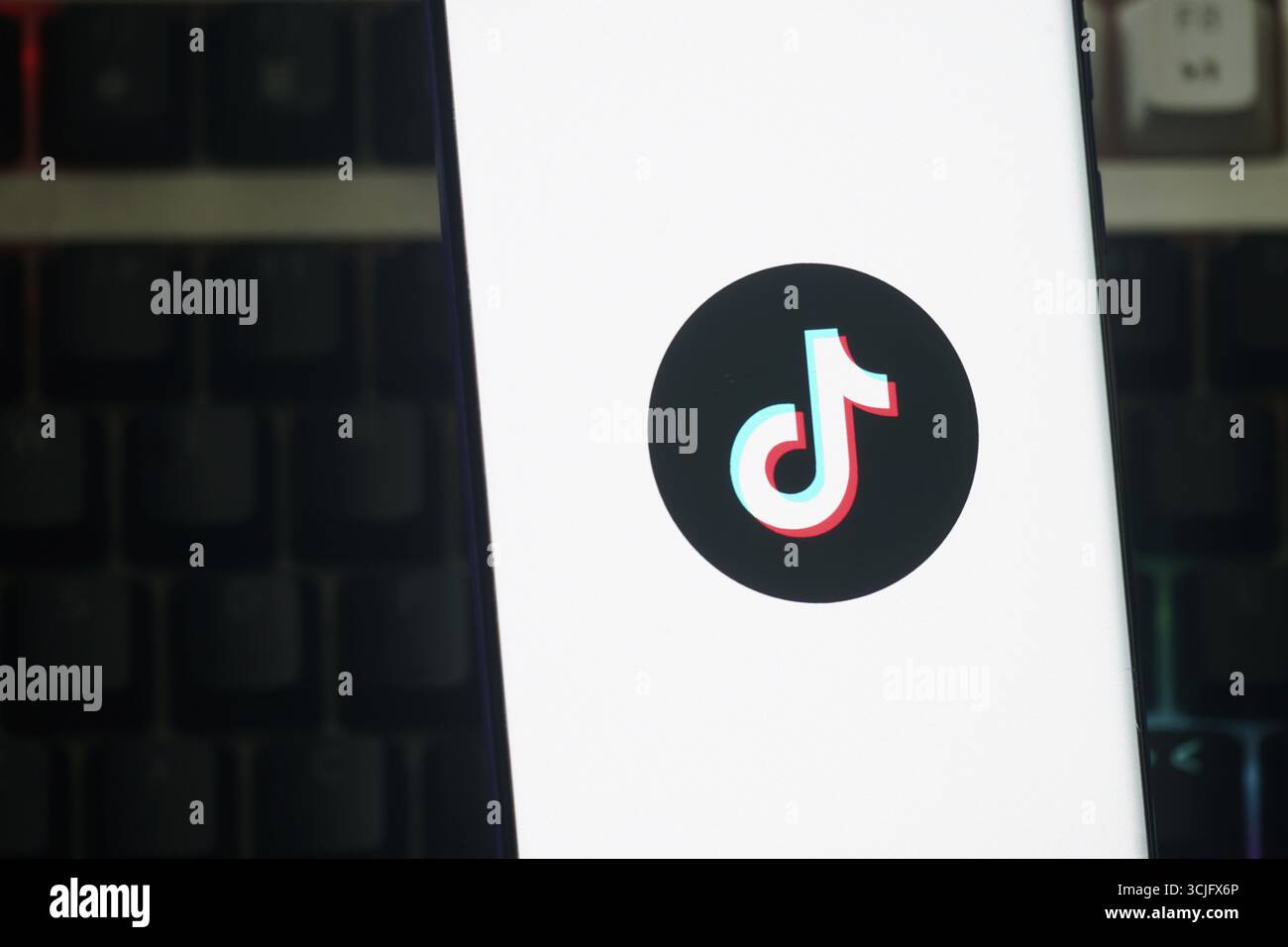 Das TikTok-Logo wird auf einem Smartphone-Bildschirm mit Tastaturhintergrund angezeigt Stockfoto