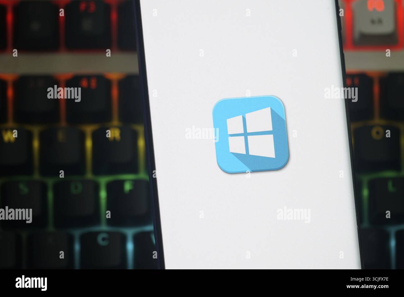 Das Windows-Logo wird auf einem Smartphone-Bildschirm vor einer bunten Tastatur angezeigt Stockfoto